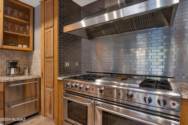 kitchen featuring backsplash, wall chimney exhaust hood, light stone counters, and double oven range