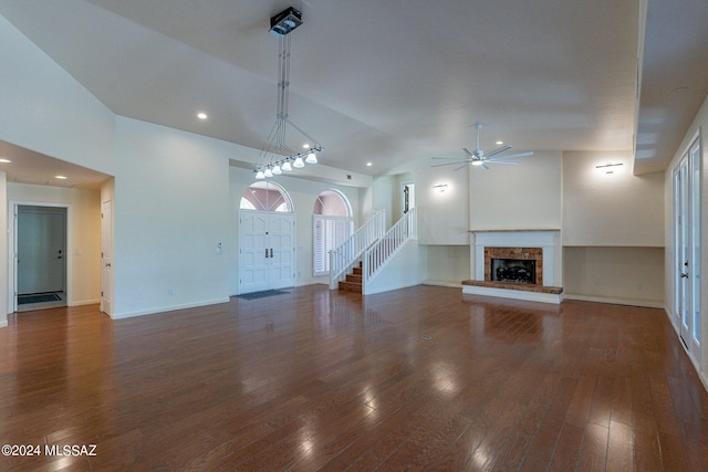 unfurnished living room with high vaulted ceiling, a fireplace with raised hearth, wood finished floors, baseboards, and ceiling fan