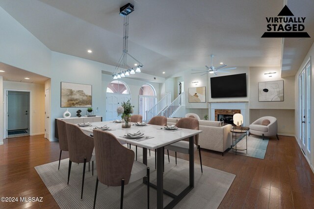 dining room with ceiling fan with notable chandelier, lofted ceiling, and dark wood-type flooring