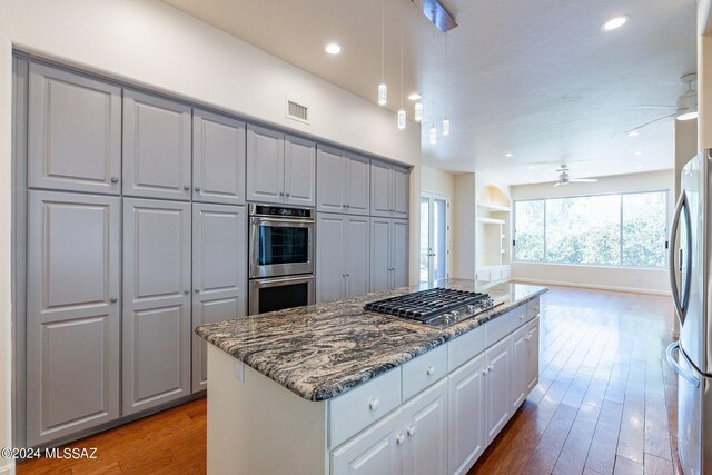 kitchen with ceiling fan, gray cabinets, appliances with stainless steel finishes, and wood-type flooring