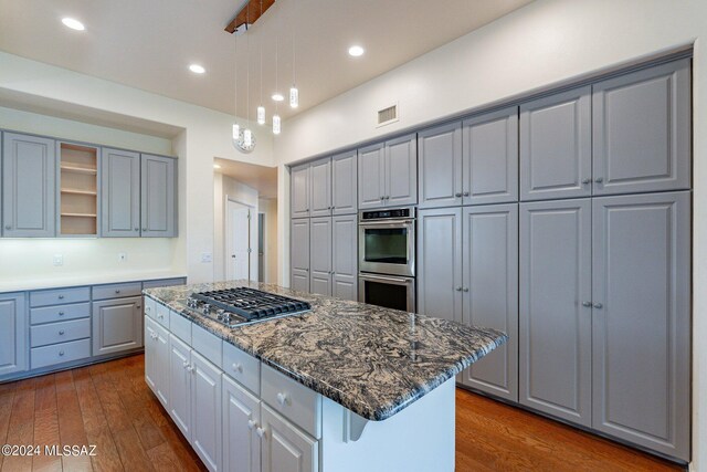 kitchen featuring appliances with stainless steel finishes, a kitchen island, dark hardwood / wood-style flooring, and gray cabinets