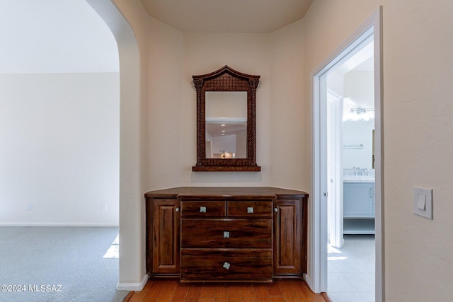 corridor with baseboards, wood finished floors, and arched walkways