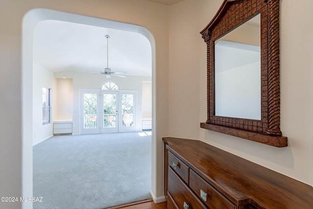 hall with light colored carpet, arched walkways, and baseboards