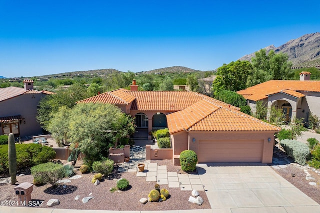 mediterranean / spanish home featuring a tile roof, concrete driveway, stucco siding, a mountain view, and a garage