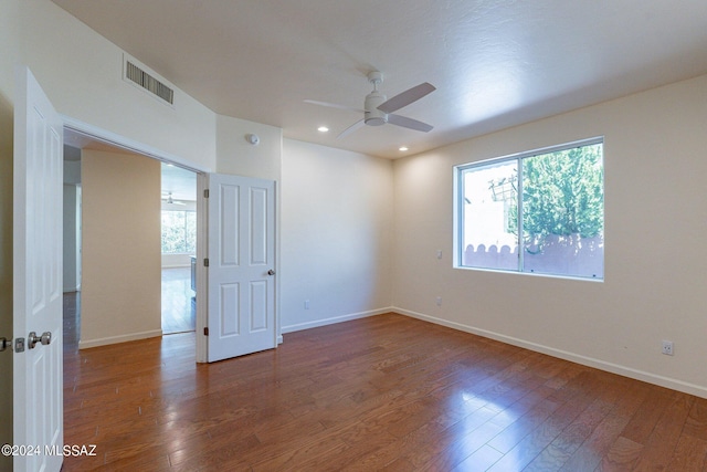 empty room with baseboards, visible vents, wood finished floors, and ceiling fan