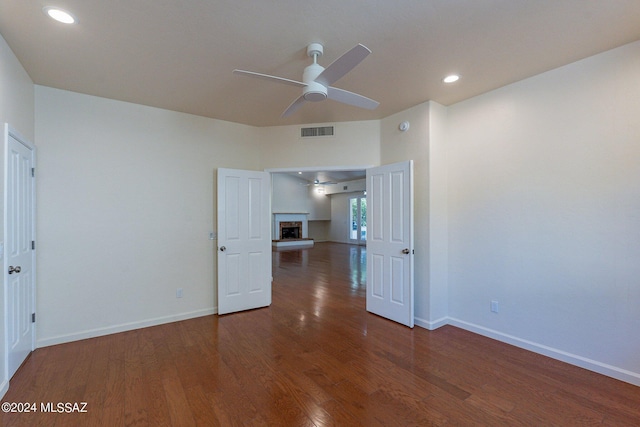 spare room with visible vents, baseboards, a fireplace with raised hearth, ceiling fan, and wood finished floors