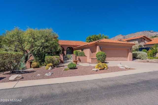 mediterranean / spanish-style home featuring stucco siding, a tile roof, an attached garage, and driveway