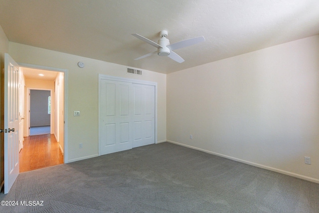 unfurnished bedroom featuring a closet, baseboards, visible vents, ceiling fan, and carpet