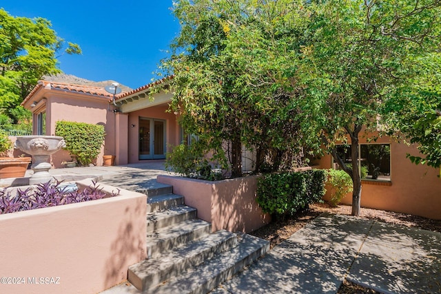 exterior space with a patio, a tile roof, french doors, and stucco siding