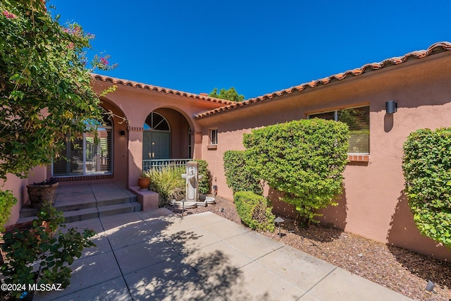 doorway to property featuring stucco siding and a porch