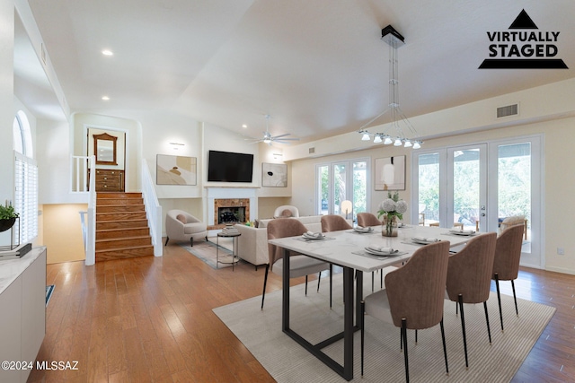 dining space featuring stairs, light wood finished floors, a fireplace, lofted ceiling, and visible vents