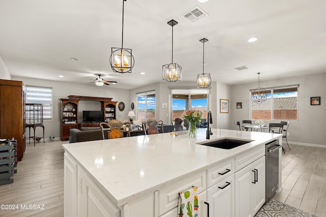 kitchen featuring light wood-type flooring, sink, an island with sink, white cabinets, and ceiling fan