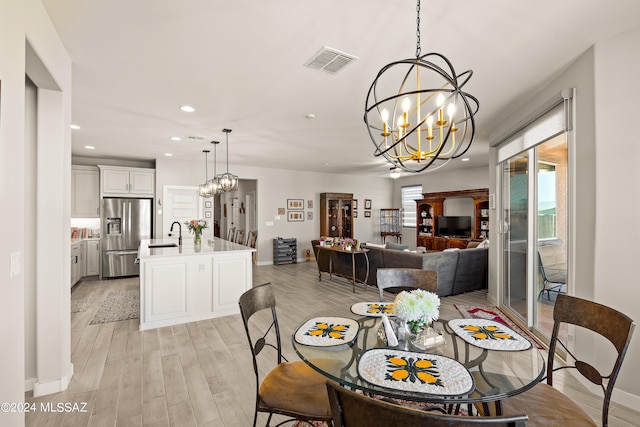 dining room with an inviting chandelier, light hardwood / wood-style floors, and sink