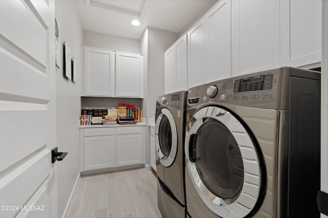 clothes washing area with cabinets, light hardwood / wood-style flooring, and washer and dryer