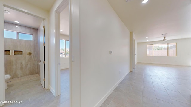 hall with a healthy amount of sunlight and light tile patterned flooring