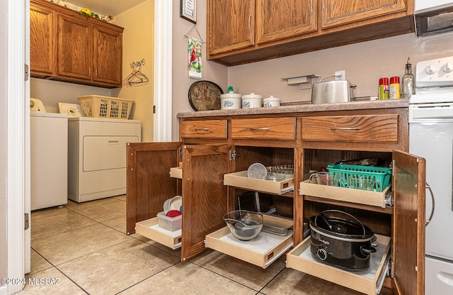 washroom featuring cabinets, light tile patterned flooring, and washer and clothes dryer