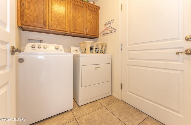 washroom with cabinets, light tile patterned floors, and washing machine and dryer