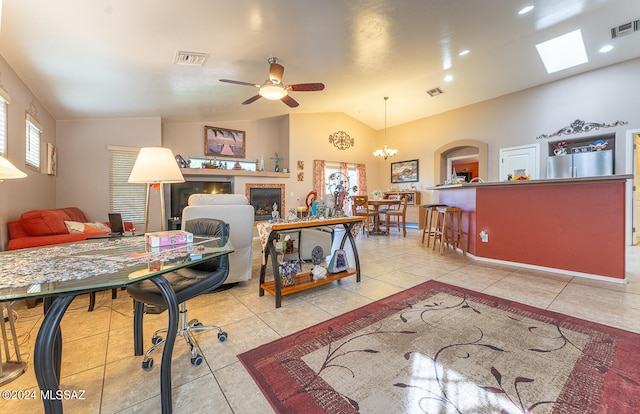 tiled office space featuring ceiling fan with notable chandelier and lofted ceiling with skylight