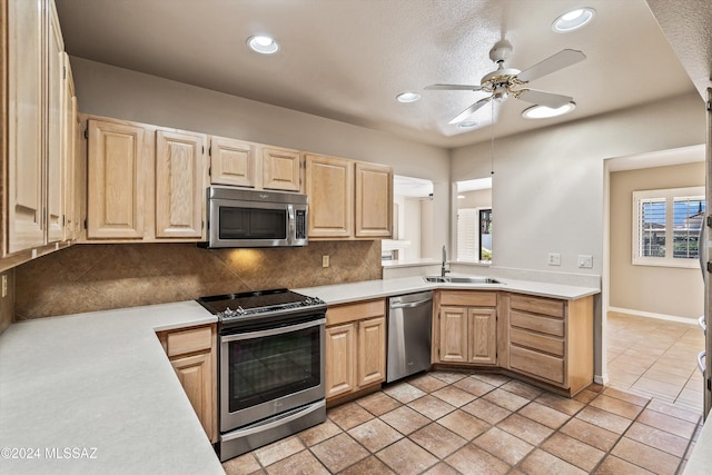 kitchen with stainless steel appliances, sink, light brown cabinetry, and decorative backsplash