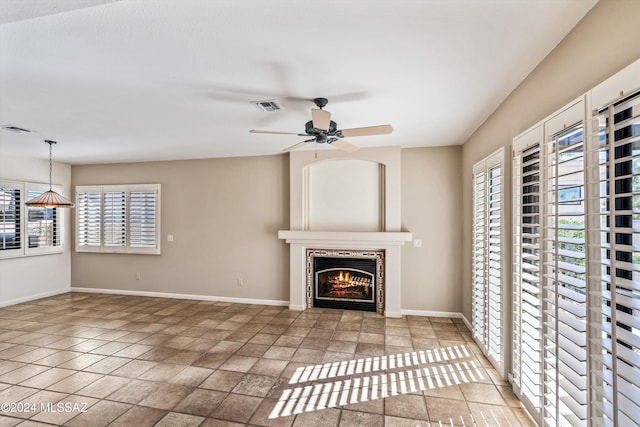 unfurnished living room featuring ceiling fan, plenty of natural light, and a fireplace