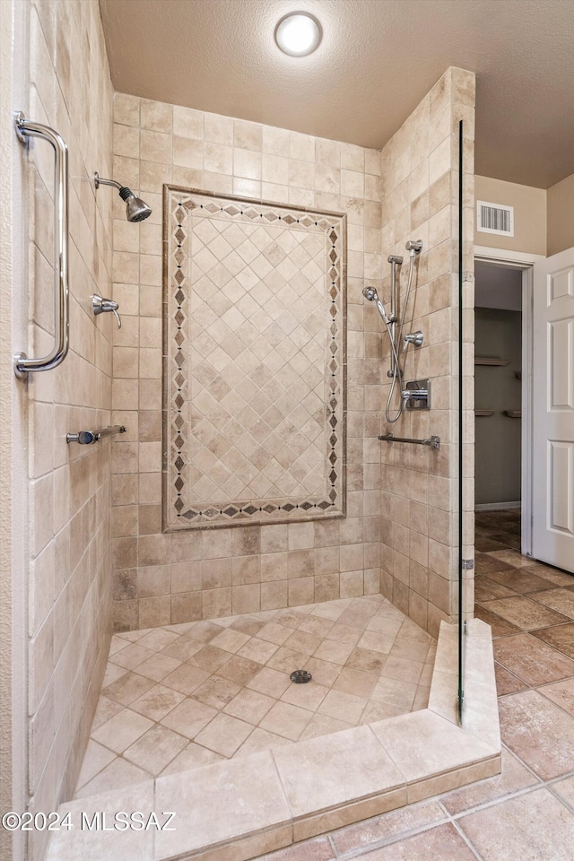 bathroom with a tile shower and a textured ceiling