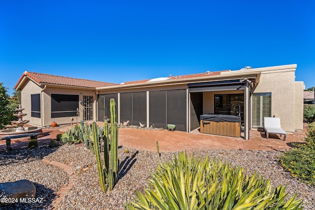 back of property with a patio area, a sunroom, and a hot tub