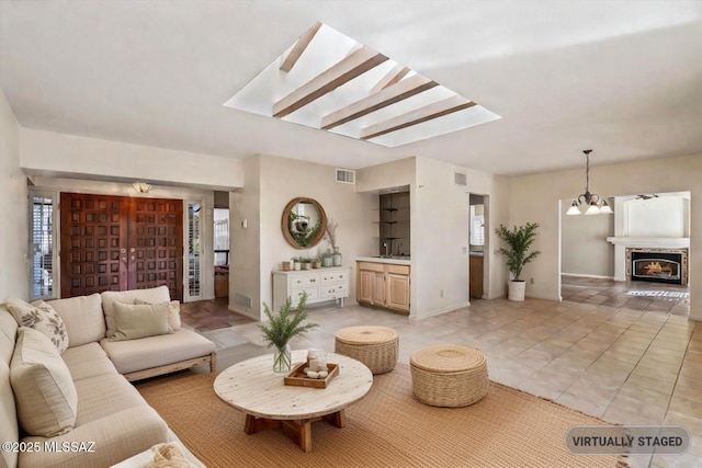 tiled living room featuring a chandelier, a skylight, and sink