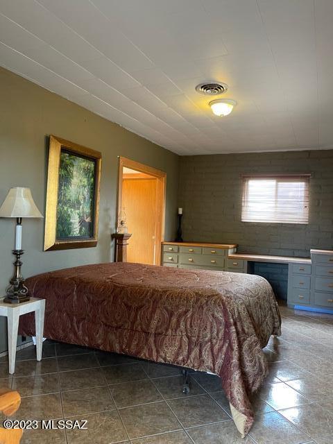 bedroom with dark tile patterned floors and visible vents