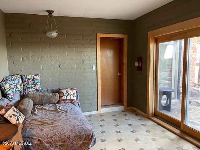 bedroom with light floors, brick wall, and multiple windows