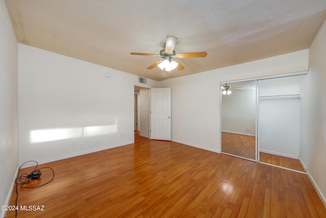 unfurnished bedroom with ceiling fan, hardwood / wood-style flooring, a closet, and a textured ceiling