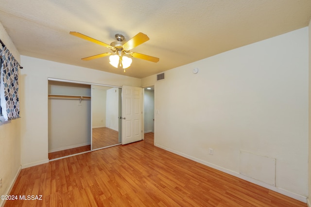 unfurnished bedroom with light hardwood / wood-style flooring, a closet, ceiling fan, and a textured ceiling