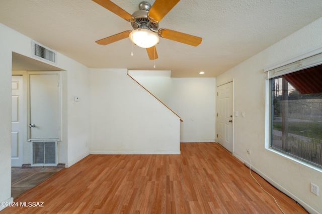 spare room with light hardwood / wood-style floors, ceiling fan, and a textured ceiling