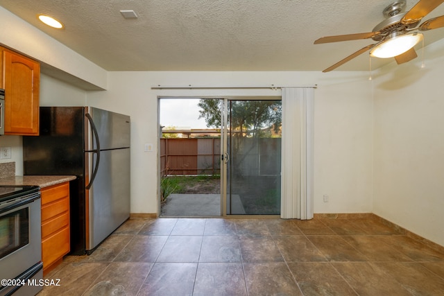 kitchen featuring dark tile patterned flooring, stainless steel appliances, ceiling fan, and a textured ceiling