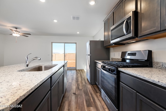 kitchen with light stone counters, a sink, visible vents, stainless steel appliances, and dark wood-style flooring