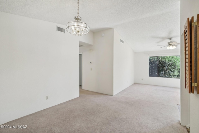 carpeted empty room featuring ceiling fan with notable chandelier, lofted ceiling, and a textured ceiling