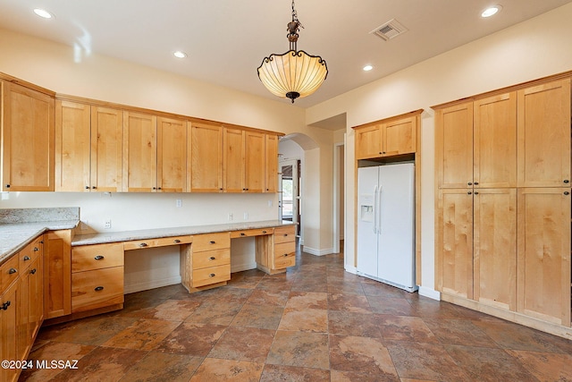 kitchen featuring pendant lighting, built in desk, white fridge with ice dispenser, and light brown cabinets