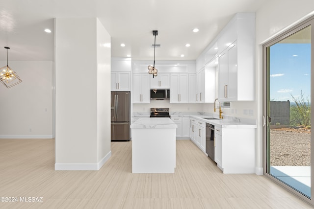 kitchen with white cabinets, sink, decorative light fixtures, appliances with stainless steel finishes, and a center island