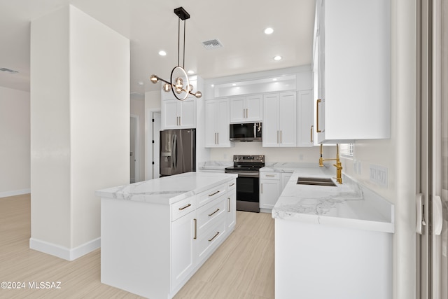 kitchen with white cabinets, pendant lighting, sink, appliances with stainless steel finishes, and a center island