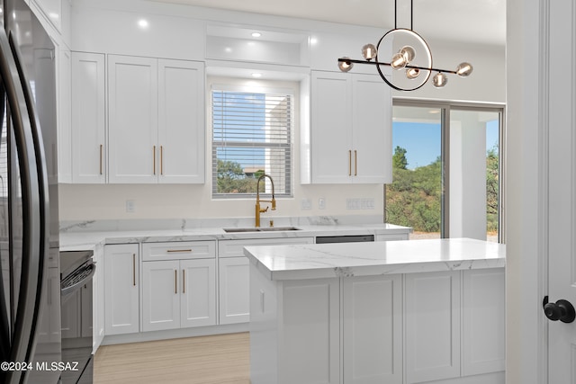 kitchen with stainless steel fridge, black stove, white cabinets, an inviting chandelier, and sink