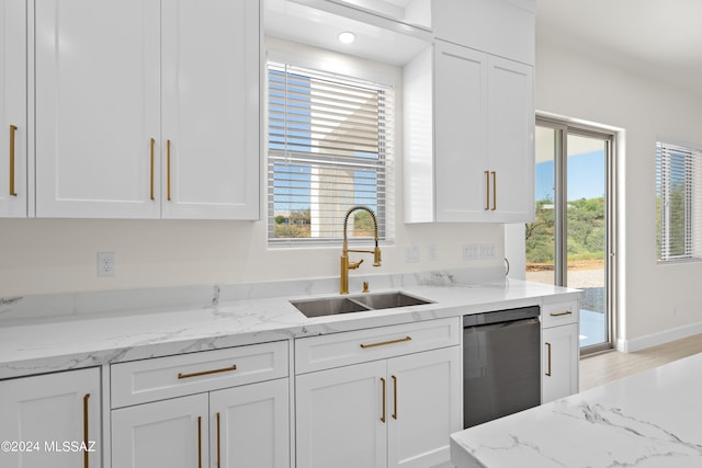 kitchen with sink, white cabinetry, light hardwood / wood-style flooring, light stone countertops, and stainless steel dishwasher