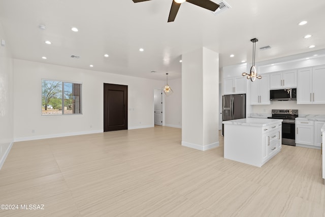 kitchen featuring appliances with stainless steel finishes, white cabinets, a kitchen island, ceiling fan, and decorative light fixtures