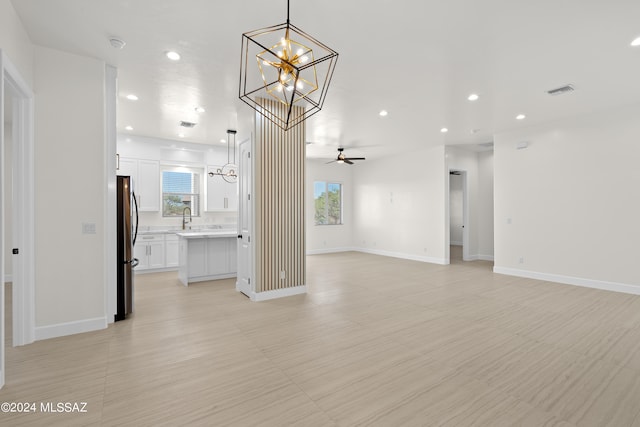 unfurnished living room featuring ceiling fan with notable chandelier and sink