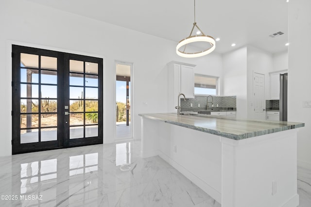 kitchen with white cabinetry, hanging light fixtures, french doors, and dark stone countertops