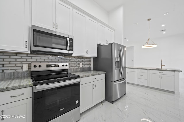 kitchen featuring sink, tasteful backsplash, pendant lighting, stainless steel appliances, and white cabinets