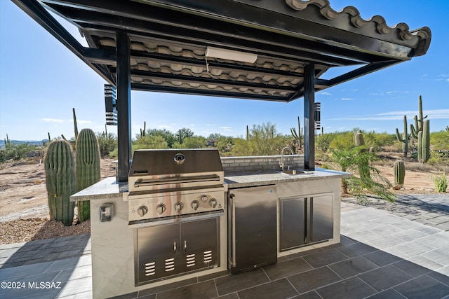 view of patio with area for grilling, a grill, and sink