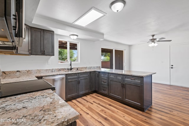 kitchen with appliances with stainless steel finishes, light hardwood / wood-style floors, kitchen peninsula, light stone countertops, and ceiling fan