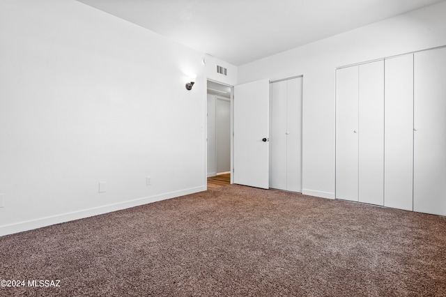 unfurnished bedroom featuring carpet floors and two closets