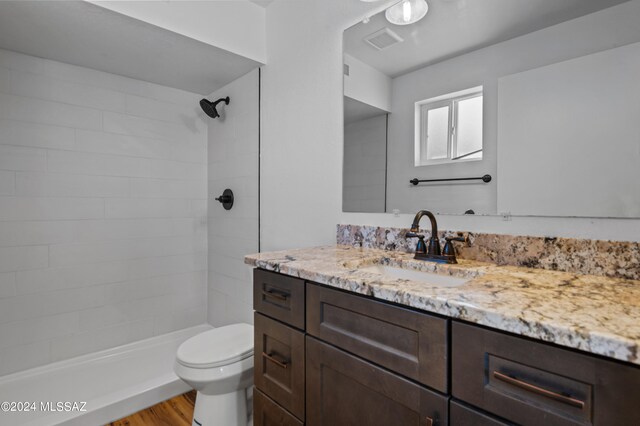 bathroom featuring a tile shower, vanity, toilet, and hardwood / wood-style flooring