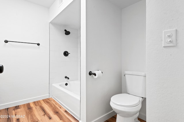 bathroom featuring wood-type flooring, tiled shower / bath combo, and toilet