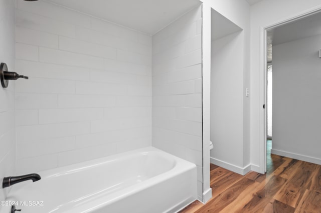 bathroom with tiled shower / bath combo, hardwood / wood-style flooring, and toilet